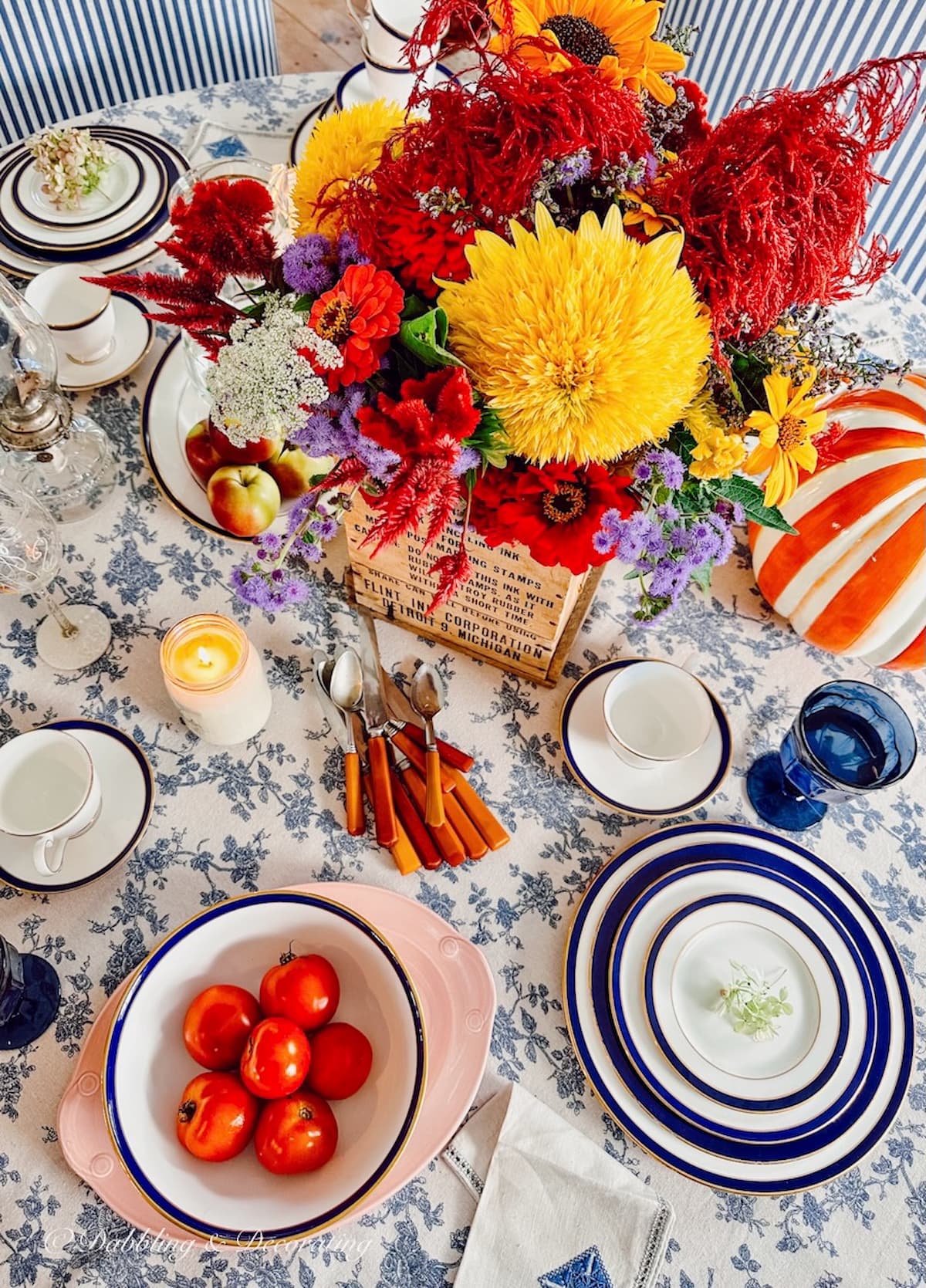 Blue and white fall decor inspired, a table with scattered vintage dishes, flowers, crate and more looking down.
