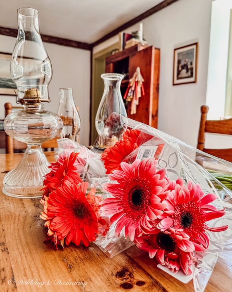 Antique oil lamps without bouquets of pink flowers on dining room table to create flower arrangements.
