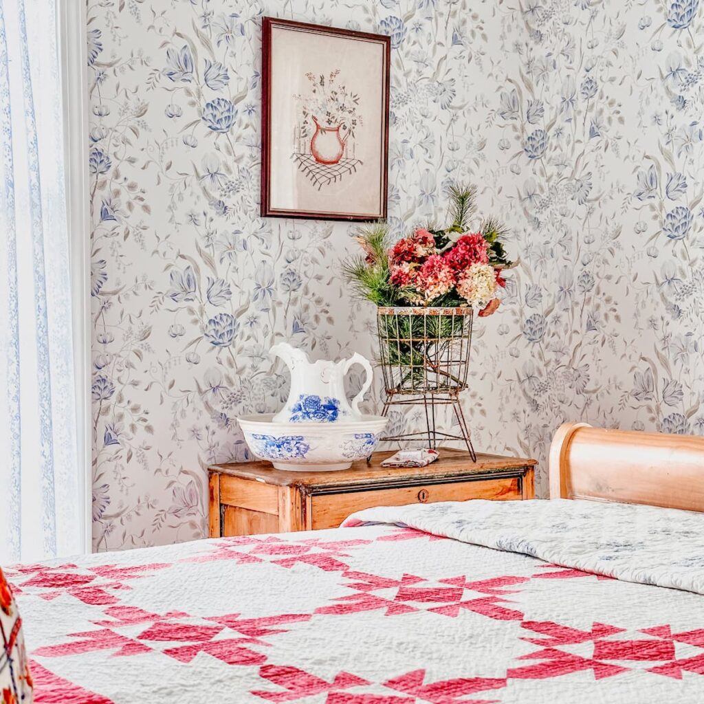 Vintage Aesthetic Bedroom with Pink Quilt, flowers, and wash basin with wallpaper.