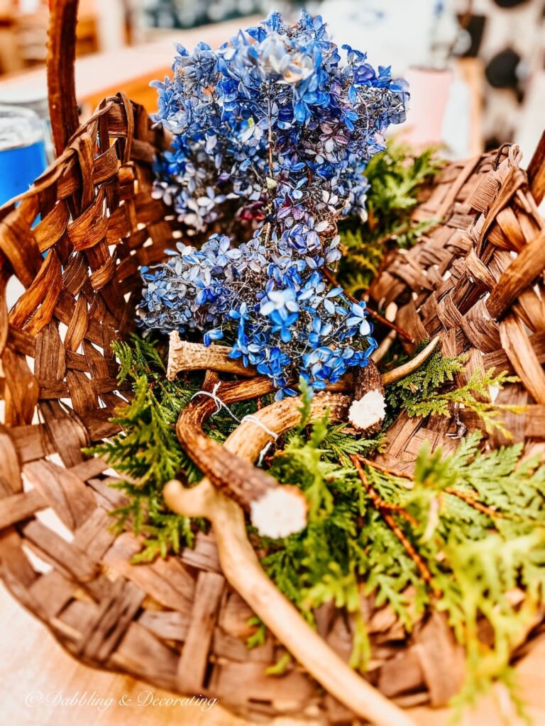Basket of Antlers, evergreens, and blue hydrangeas