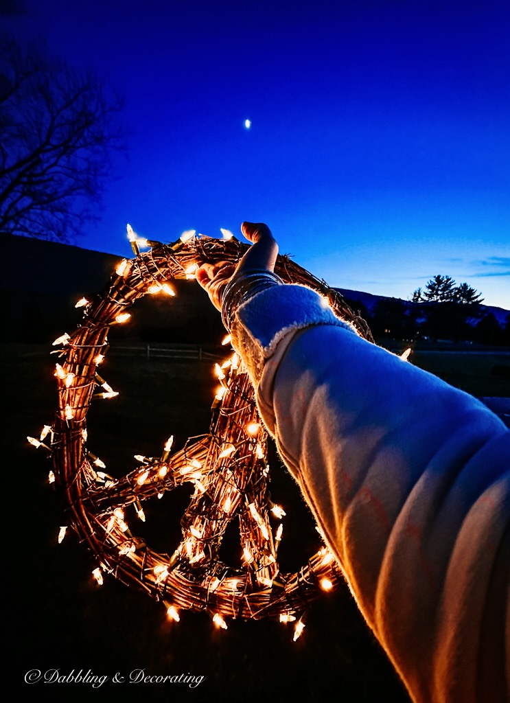 A person holding a peace sign with lights around it.