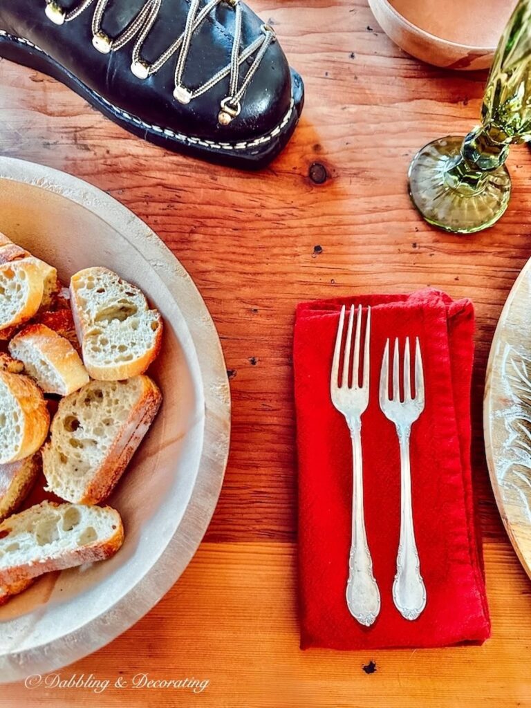 A plate of bread and forks on a rustic wooden table.