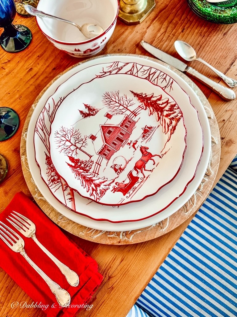 A cabin-themed Winter table setting with red and white plates and silverware.