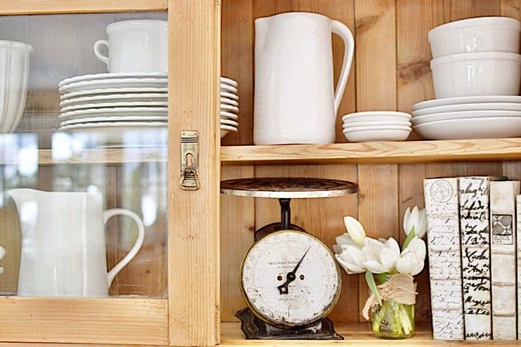 Vintage Hutch with white dishes, vintage scale and old books with white tulips.