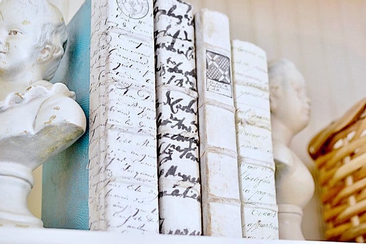 Vintage blue and white books on bookshelf with small antique white busts as bookends.
