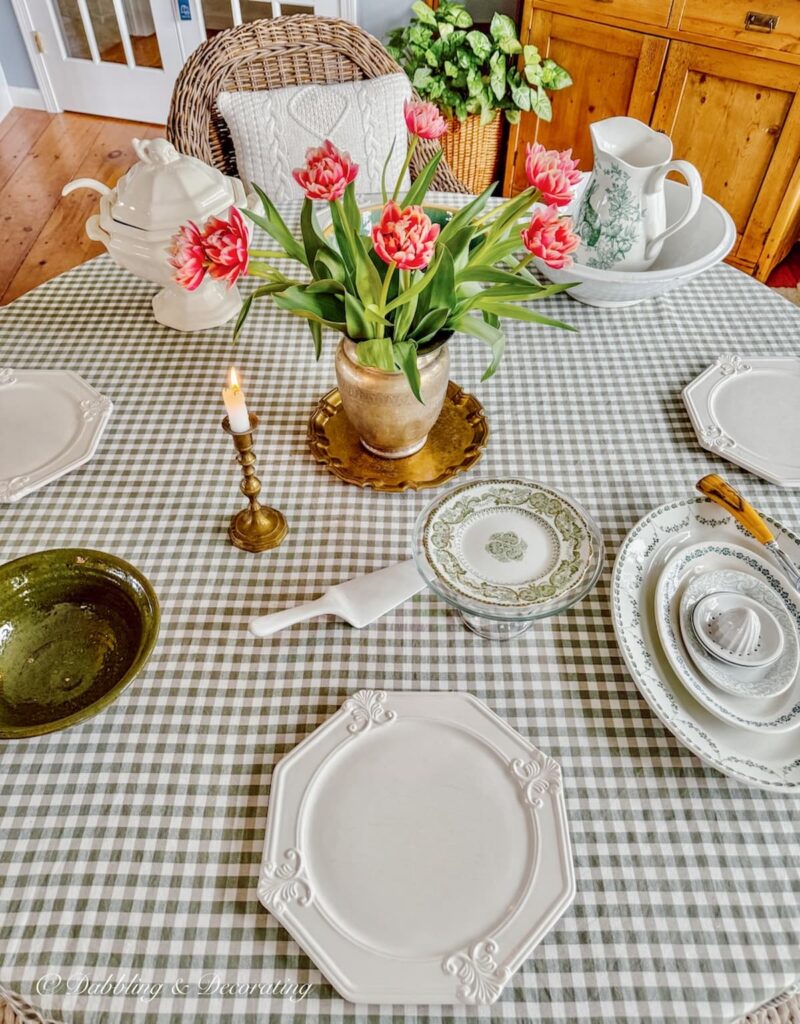 Easter styled dining room table with pink striped tulip arrangements in silver pitcher paired with a gold platter.