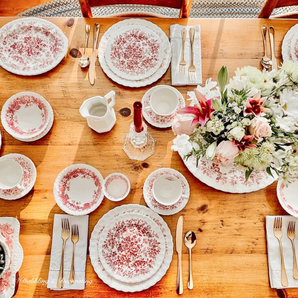 Warm winter tablescape with pink and white dishes on a pine table with collected style.