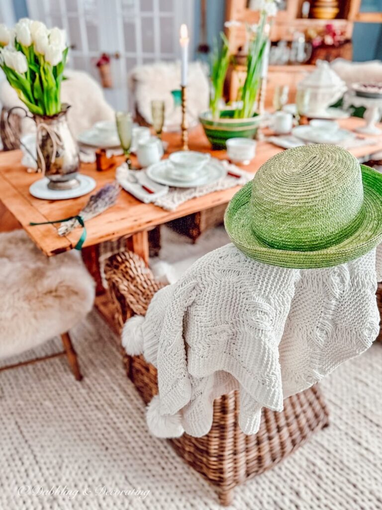 Green Irish Top Hat with Knitted Blanket on Wicker Chair at Table.