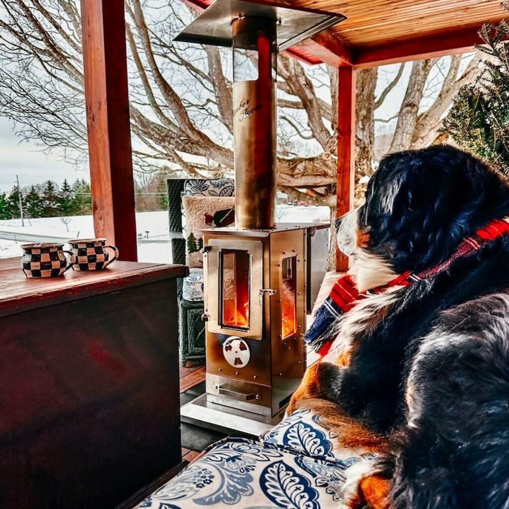 Bernese Mountain Dog in front of Big Timber outdoor pellet heater on Porch. Winter decor style.