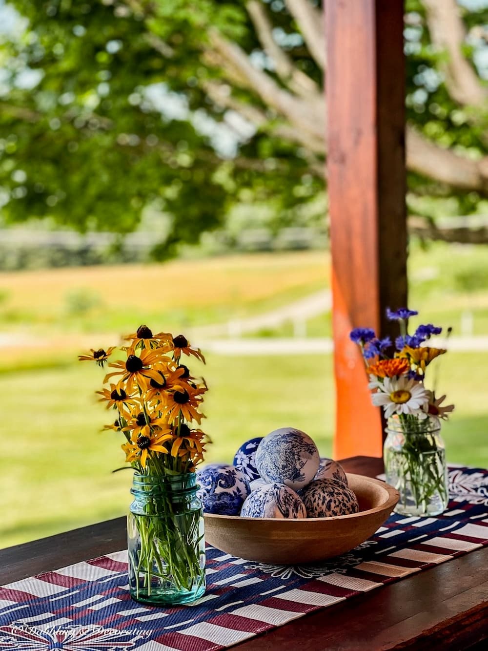 blue and white gifts for her with blue and white chinoiserie balls in wooden bowl on porch table with spring flowers.