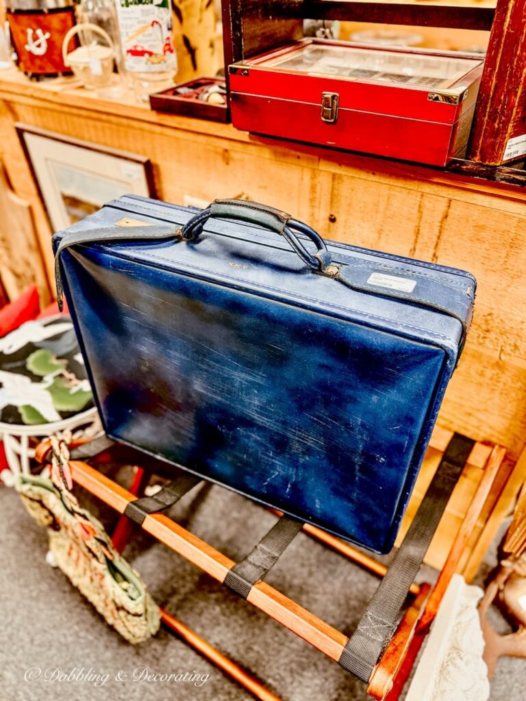 Blue Hartman luggage suitcase on luggage rack in vintage bedroom decor.