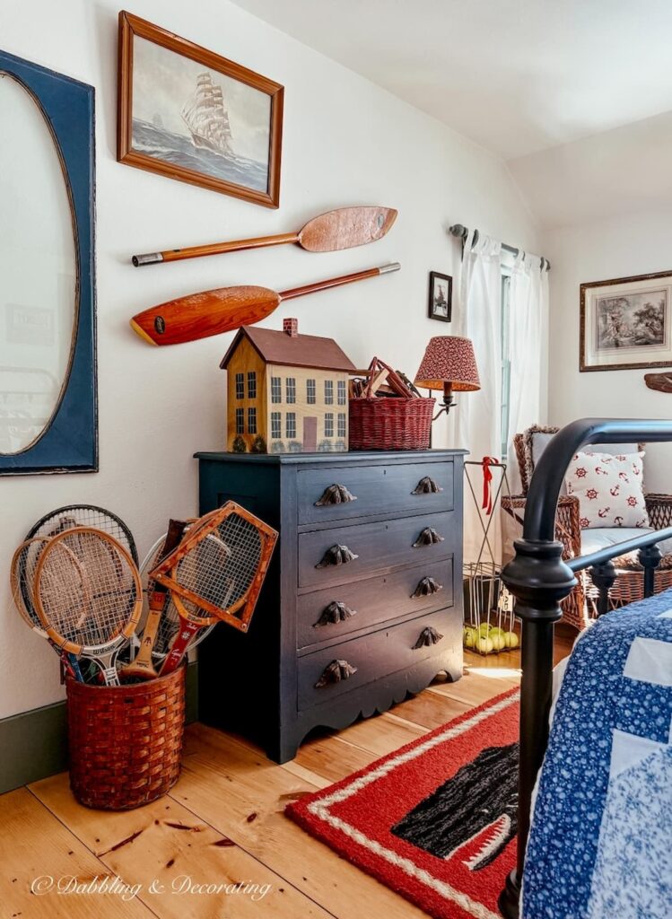 Vintage styled coastal bedroom with red and blue accents with a thrifted wooden house box on dresser inside our Coastal Maine home tour.