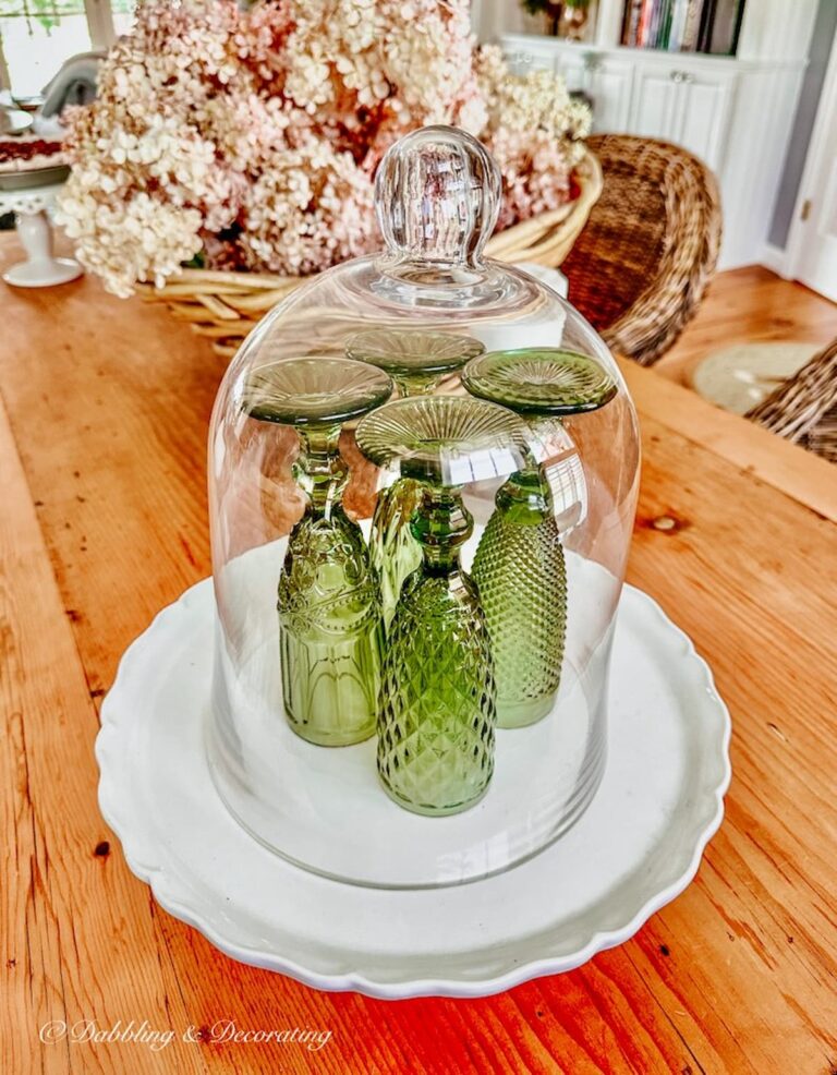 Green Flutes on Dining Room Table Displayed Under a Glass Cloche