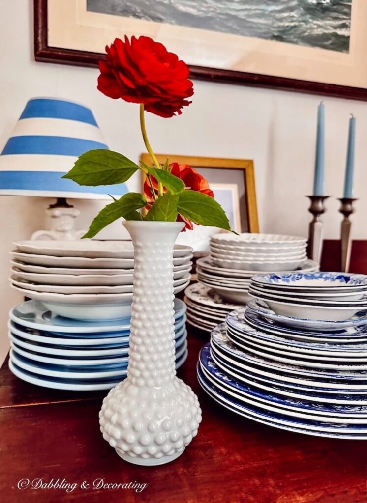 Hobnob Milk glass bud vase with flower and dishes on table.