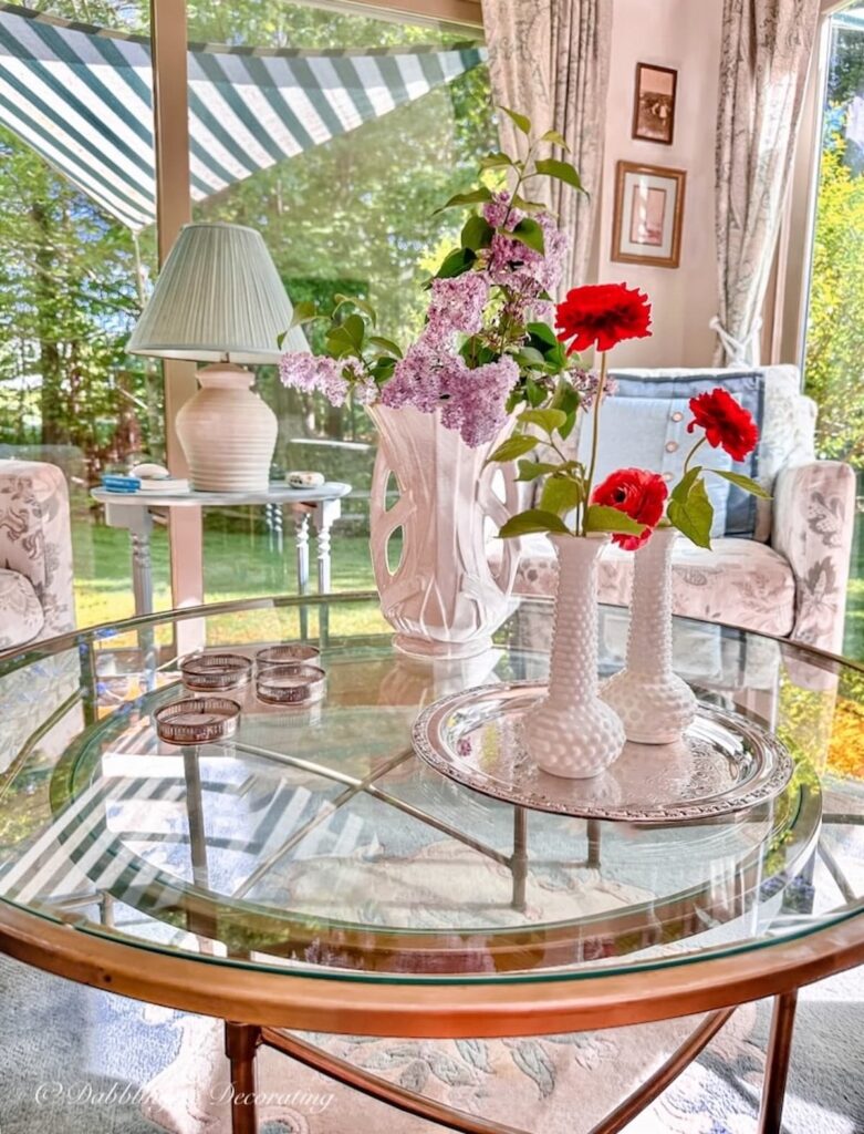 Sunroom with Summer Coffee Table Decor with vintage finds in Maine. and a sun shade sail awning on green and white striped over the windows.