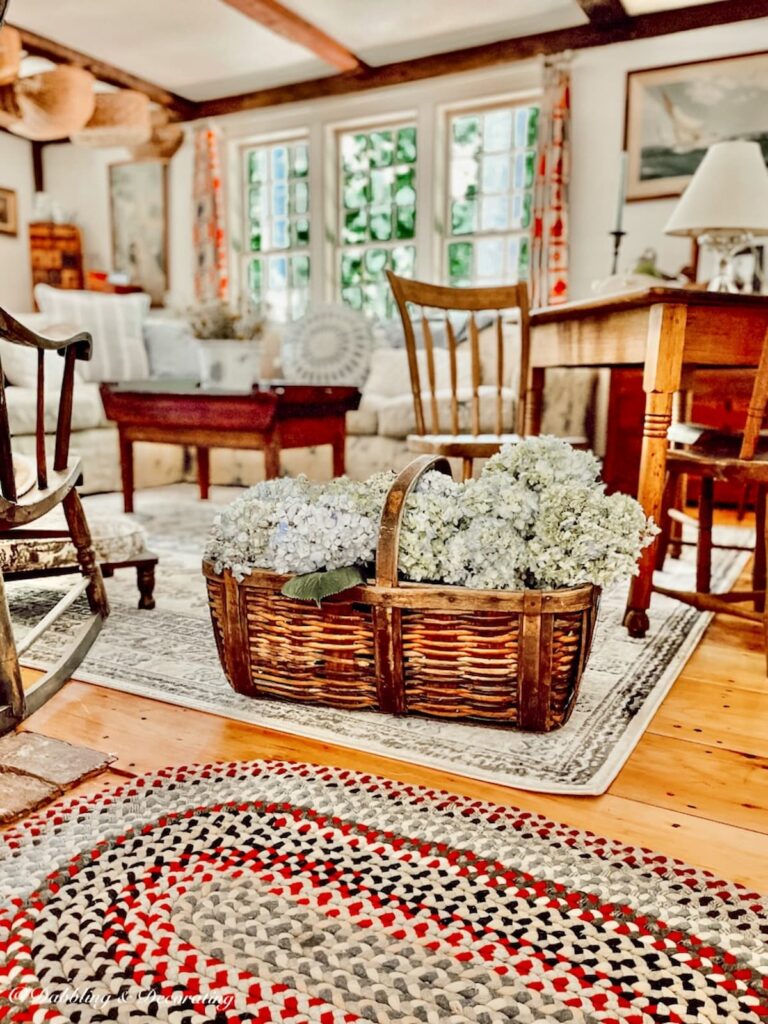 Antique basket with blue hydrangeas in cottage vintage style living room.