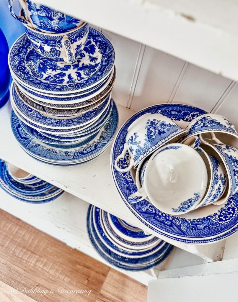 Vintage blue and white dishes,bowls, and teacups on white thrift shop shelving.