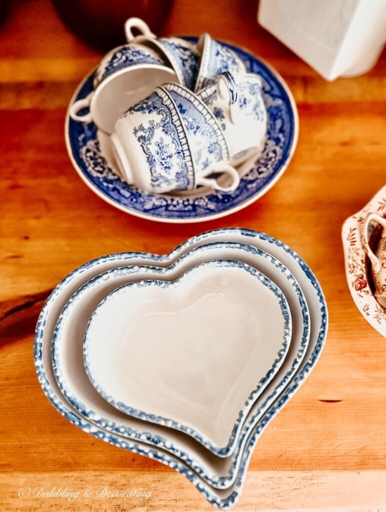 Blue and white vintage bowl with tea cups and nesting heart ceramic home accents thrifted on kitchen counter.