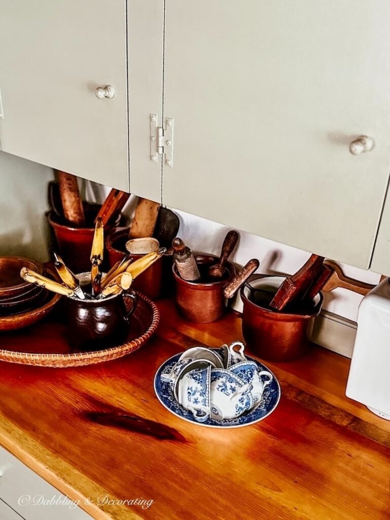 Blue and white antique bowl with tea cups on vintage country kitchen counter with brown accents.