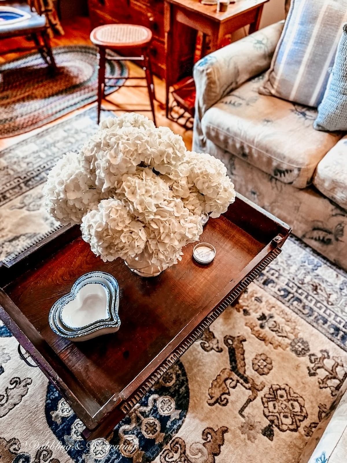 Vintage home living room coffee table with white hydrangeas and blue and white nesting heart bowls.