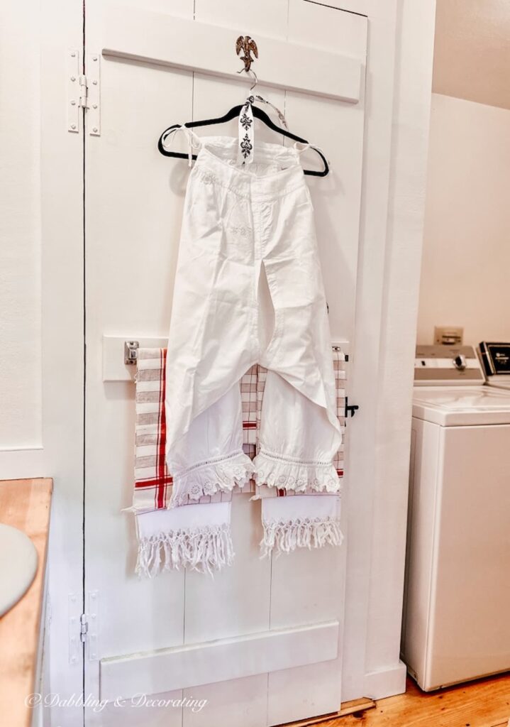 Antique white bloomers with French linens hanging on bathroom vintage door.