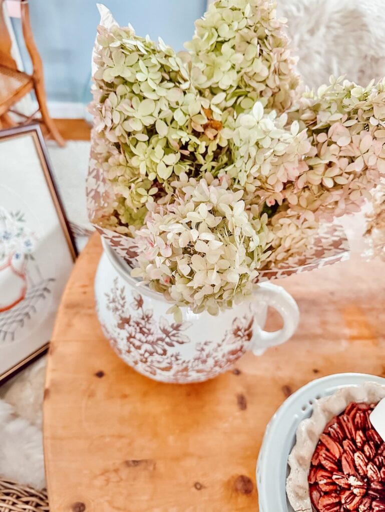Brown transferware large pitcher with fall hydrangeas on table.