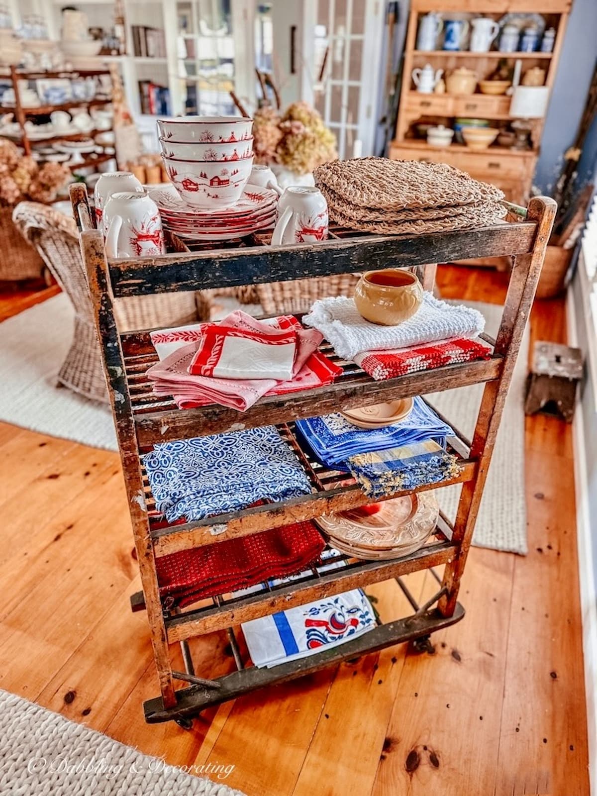 Vintage style dining room with fall centerpiece and vintage cobbler rack with vintage collections as a room divider in open floor plan space.