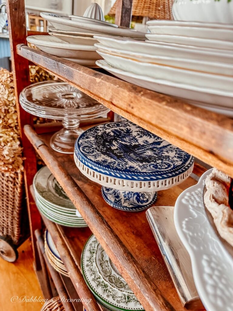Vintage cake stands lined up on vintage cobbler rack shelf.
