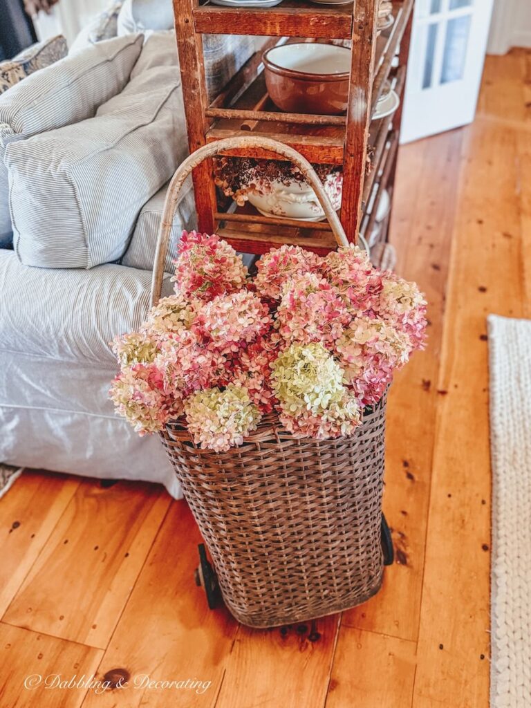 Pink hydrangeas in French basket displayed in living room for fall.