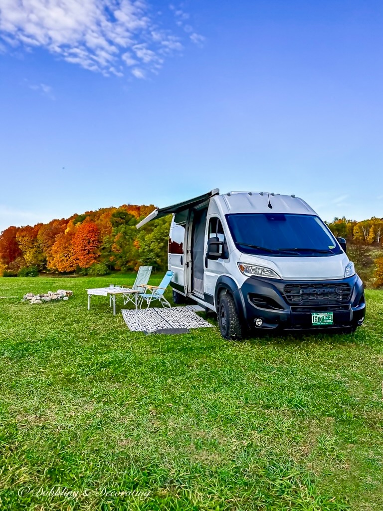 White RV with camp set up outside during peak foliage.