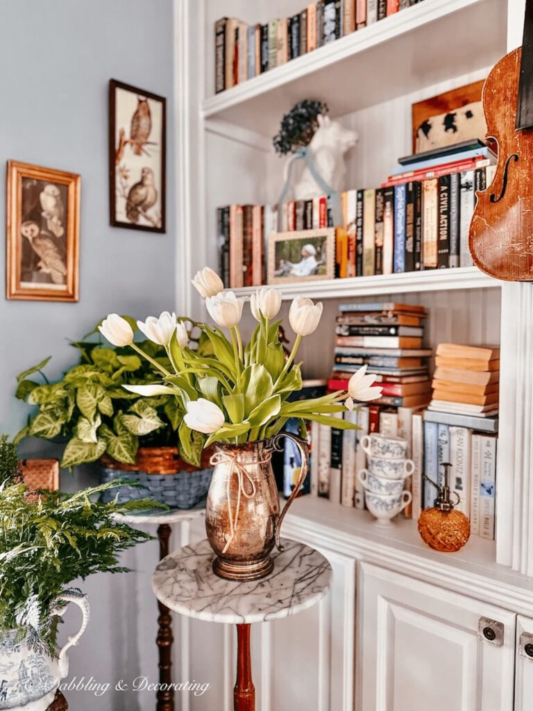 White tulips in a silver vintage pitcher in a corner nook.