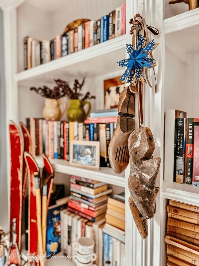 Vintage cobbler shoes hanging on bookshelving as vintage Christmas decorations.