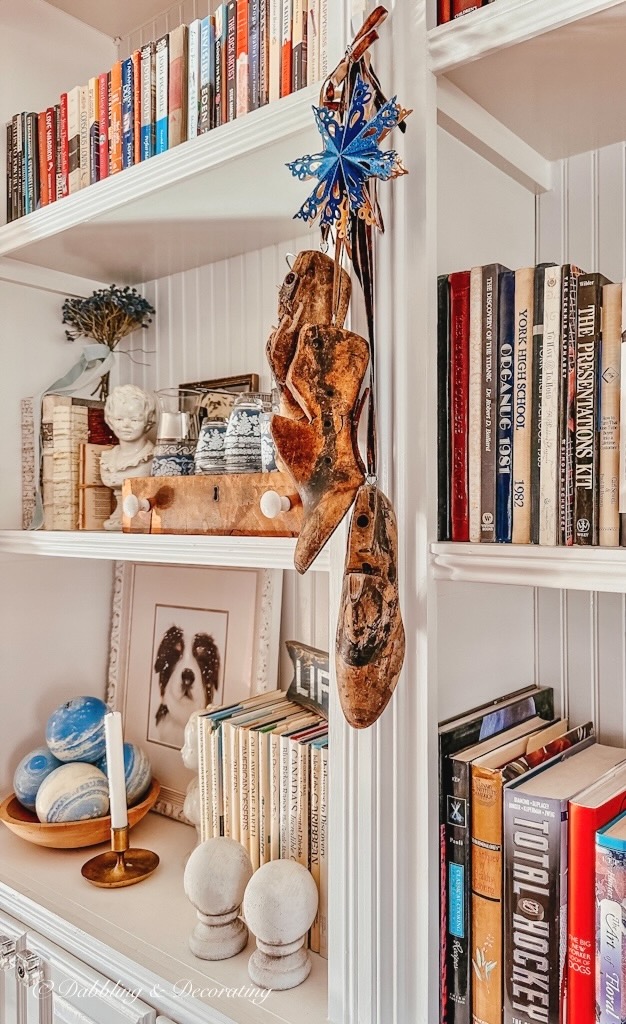 Vintage cobbler shoes hanging on bookshelving as vintage Christmas decorations.