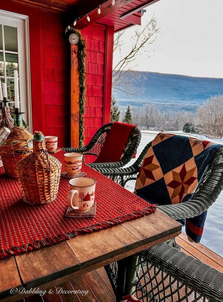 Quilts and blankets on the back of chairs on an Apres ski theme porch around a table in the mountains.
