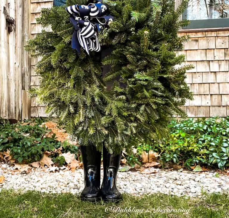 Large Christmas wreath with coastal blue bow and person holding it.