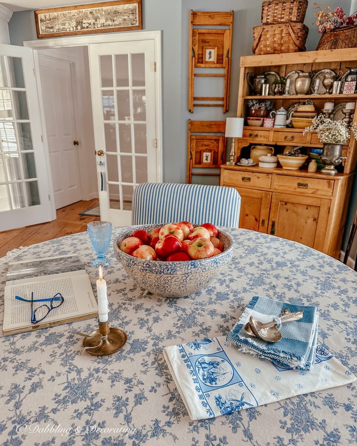 BLUE AND WHITE DINING ROOM STYLED TABLE WITH BOWL OF APPLES, VINTGE WALL DECOR AND VINTAGE HUTCH . Thrift Store decor ideas.