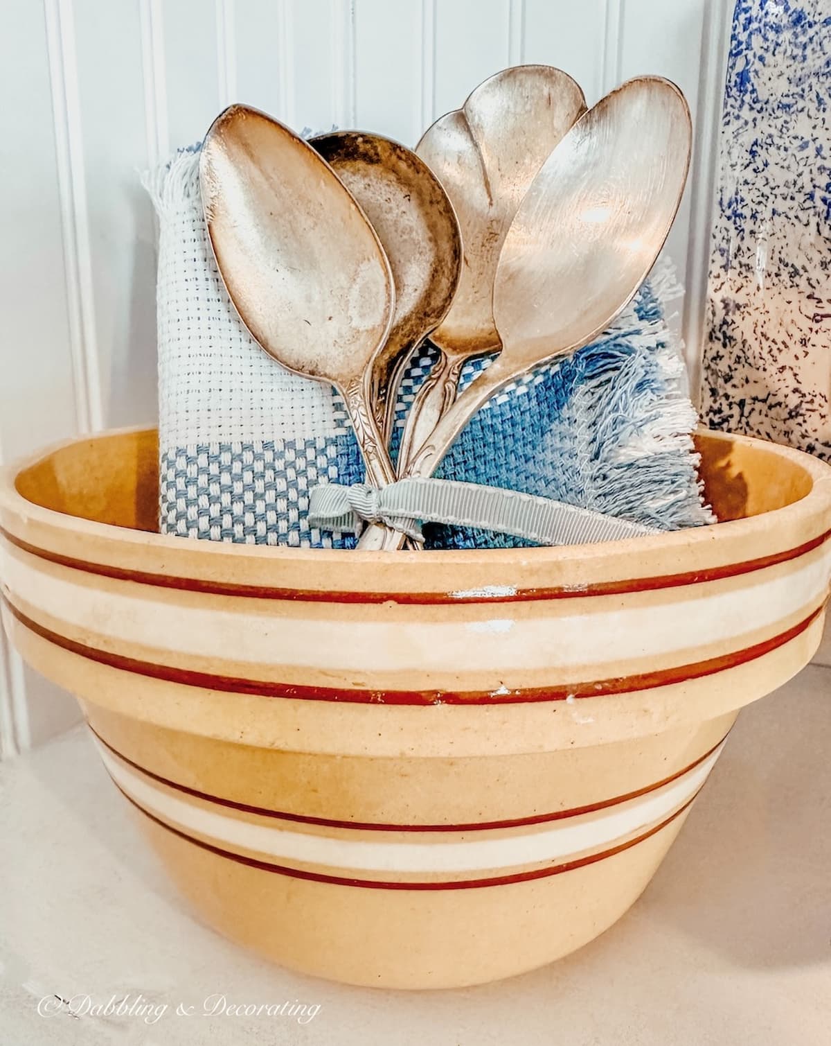 Vintage Yellow ware bowl with brown stripes with blue linens and silver spoons.