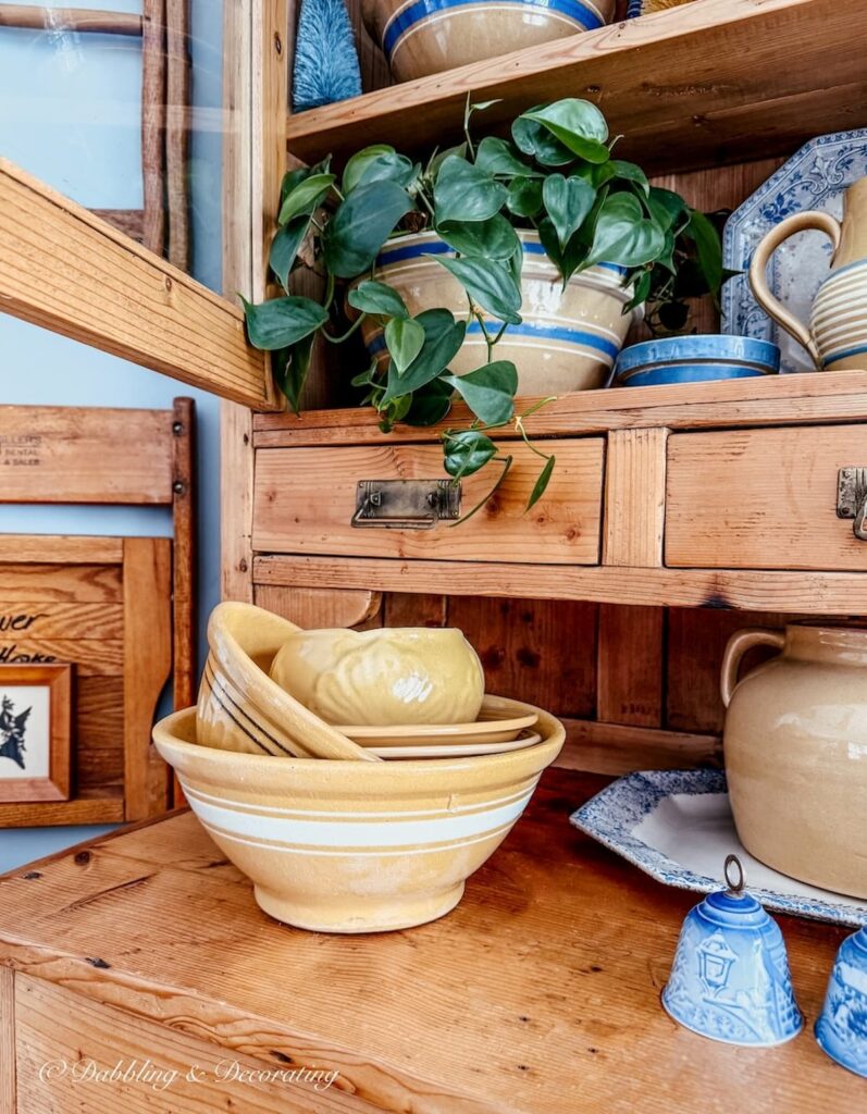 Vintage hutch with stacked yellowware bowls and blue accents.