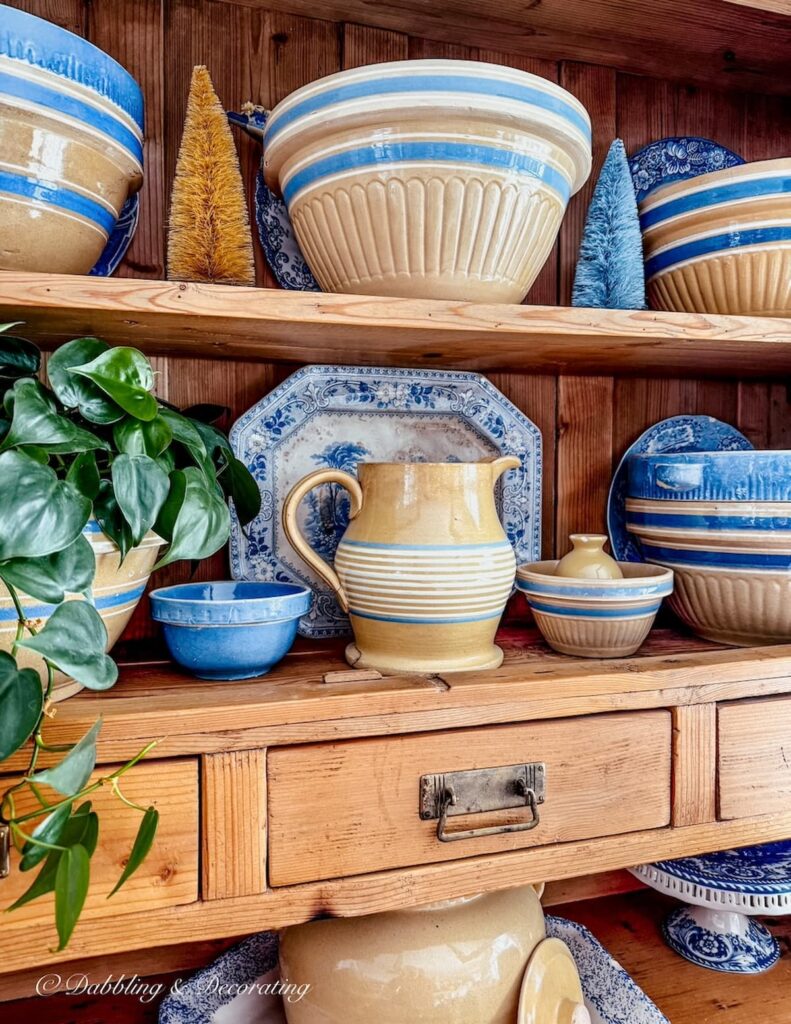 Vintage dining room pine hutch layered with yellowware bowls and pitchers with blue accents.