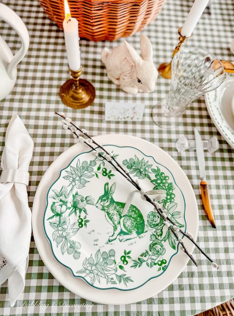 Green and white place setting with pussy willows tied with a ribbon on green and white gingham table.