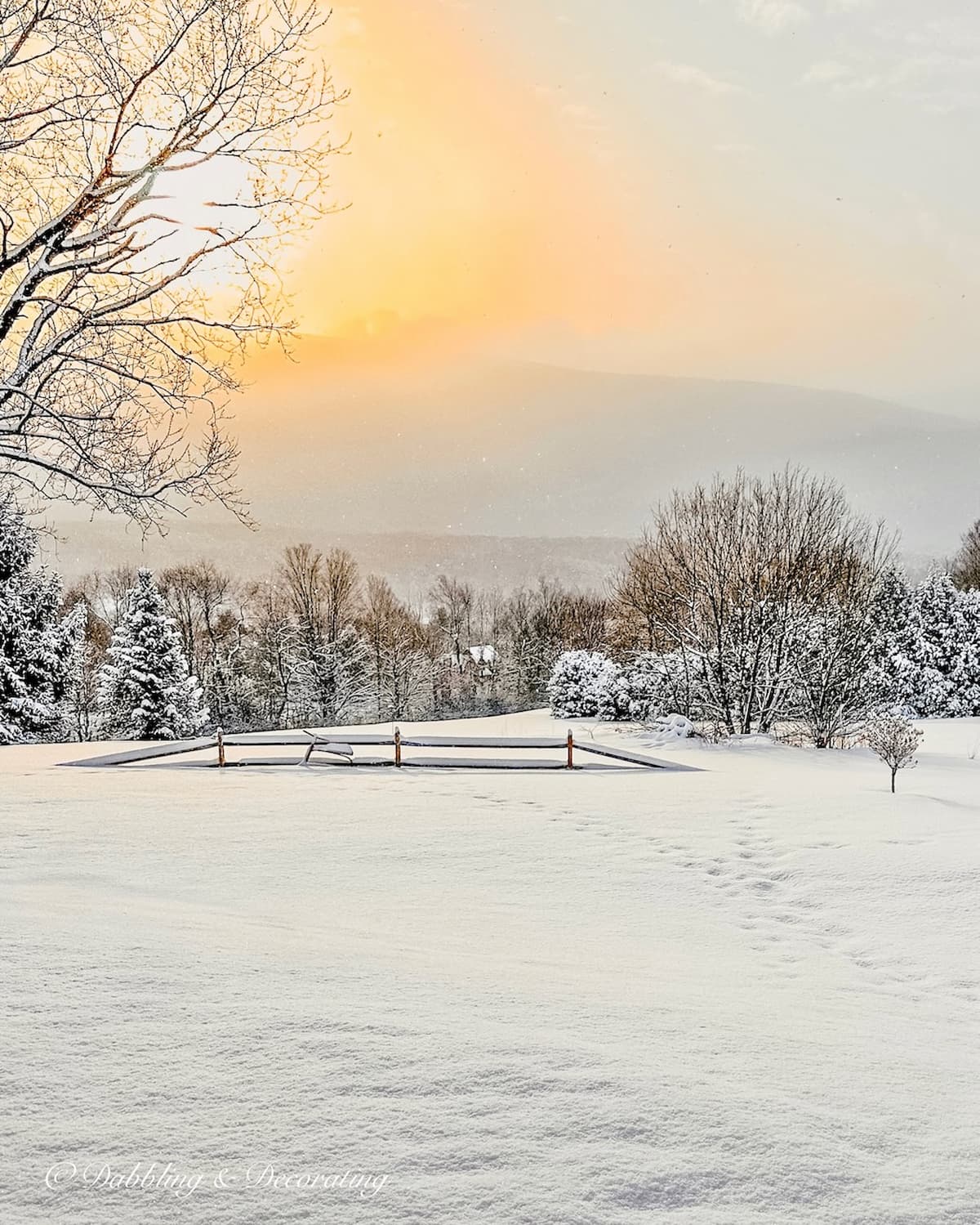 Mountain sunrise with snow and split rail fence with vintage red ski bob from France.