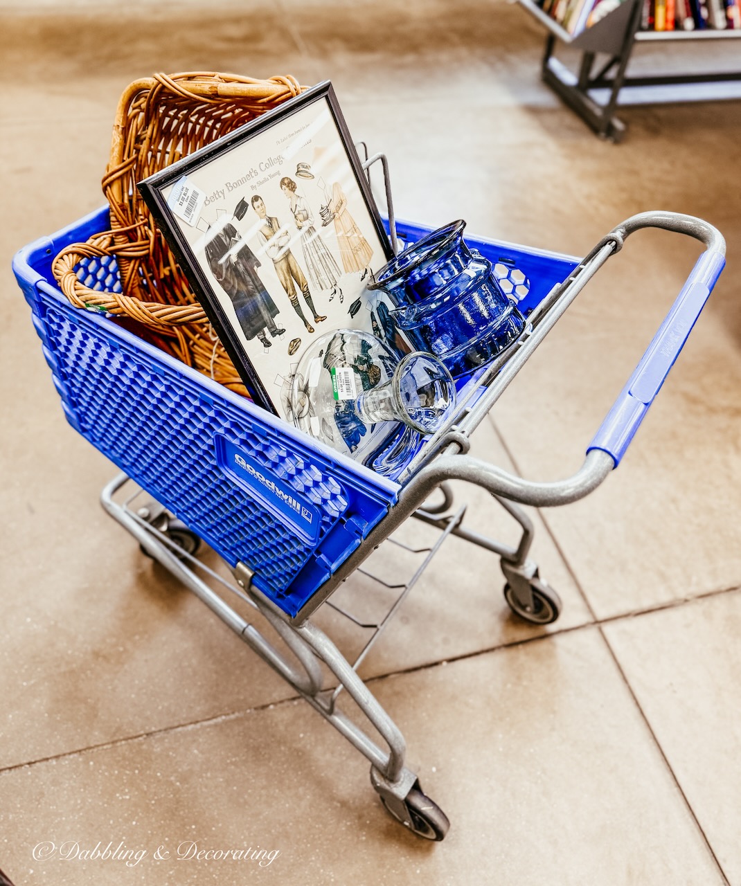 Blue shopping cart filled with home decor finds at Goodwill Northern New England Manchester, NH.