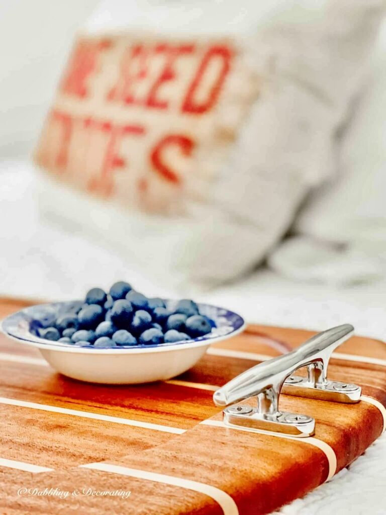 Bowl of blueberries on nautical serving tray wooden with silver boat handles.