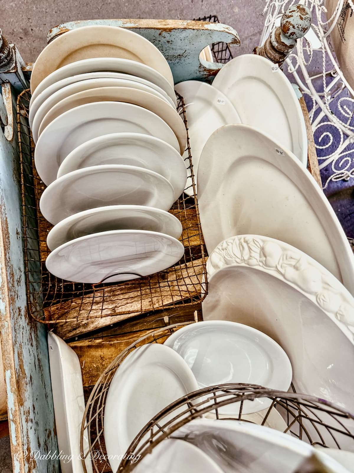 White vintage ironstone plates and platters displayed at antique booth.
