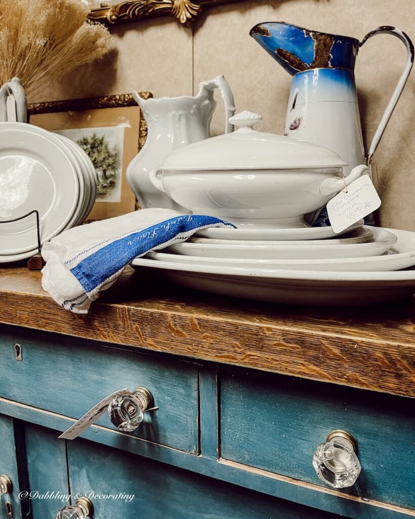 Antique blue dresser with white ironstone display in antique store.