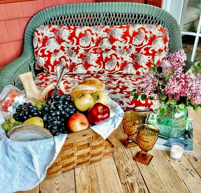 Old Fashioned picnic basket with fruit on pallet coffee table on porch.