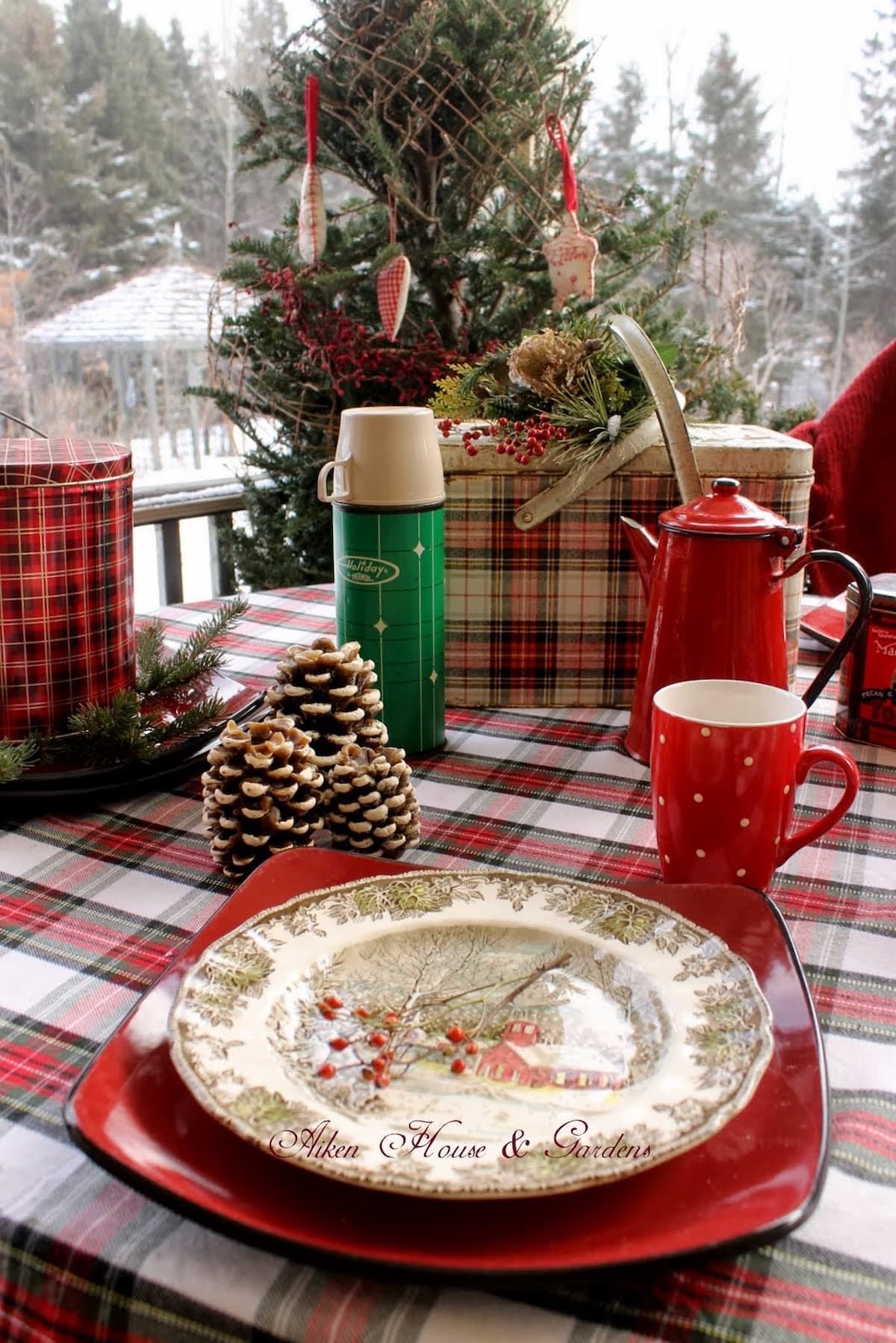 Plaid Christmas picnic on the porch with vintage picnic baskets, thermoses, and pine tree in apres ski decor by White Arrows Home.