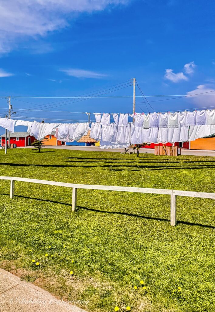 Clothesline sheets in Newfoundland with colorful homes seaside.