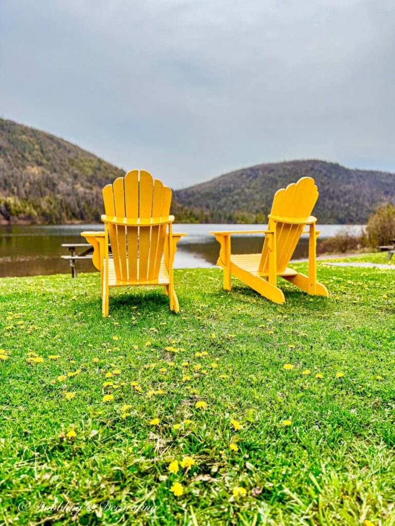 Two Yellow Adirondack chairs o green lawn at KOA campground in Gros Morne National Park Newfoundland an example of coastal cottage décor ideas.