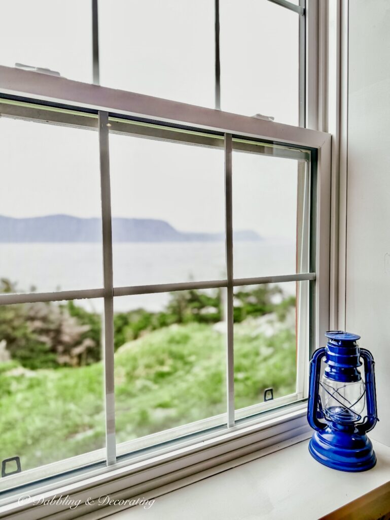 Blue lantern on white windowsill overlooking ocean in Lobster Cove Lighthouse Rocky Harbour, NL